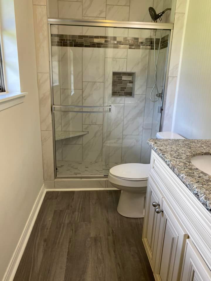 A bathroom with a toilet , sink and shower.