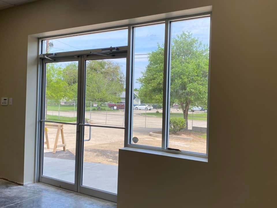 An empty room with a large window and sliding glass doors.