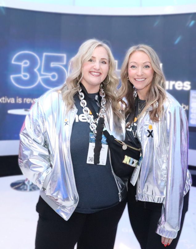 Man with headphones dances joyfully, holding phone, lit by pink and blue light.