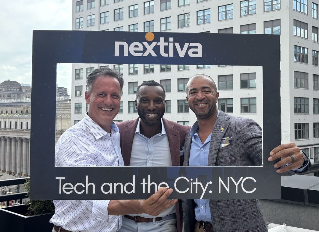 Man with glasses wearing a headset, gesturing during a video call at his desk.