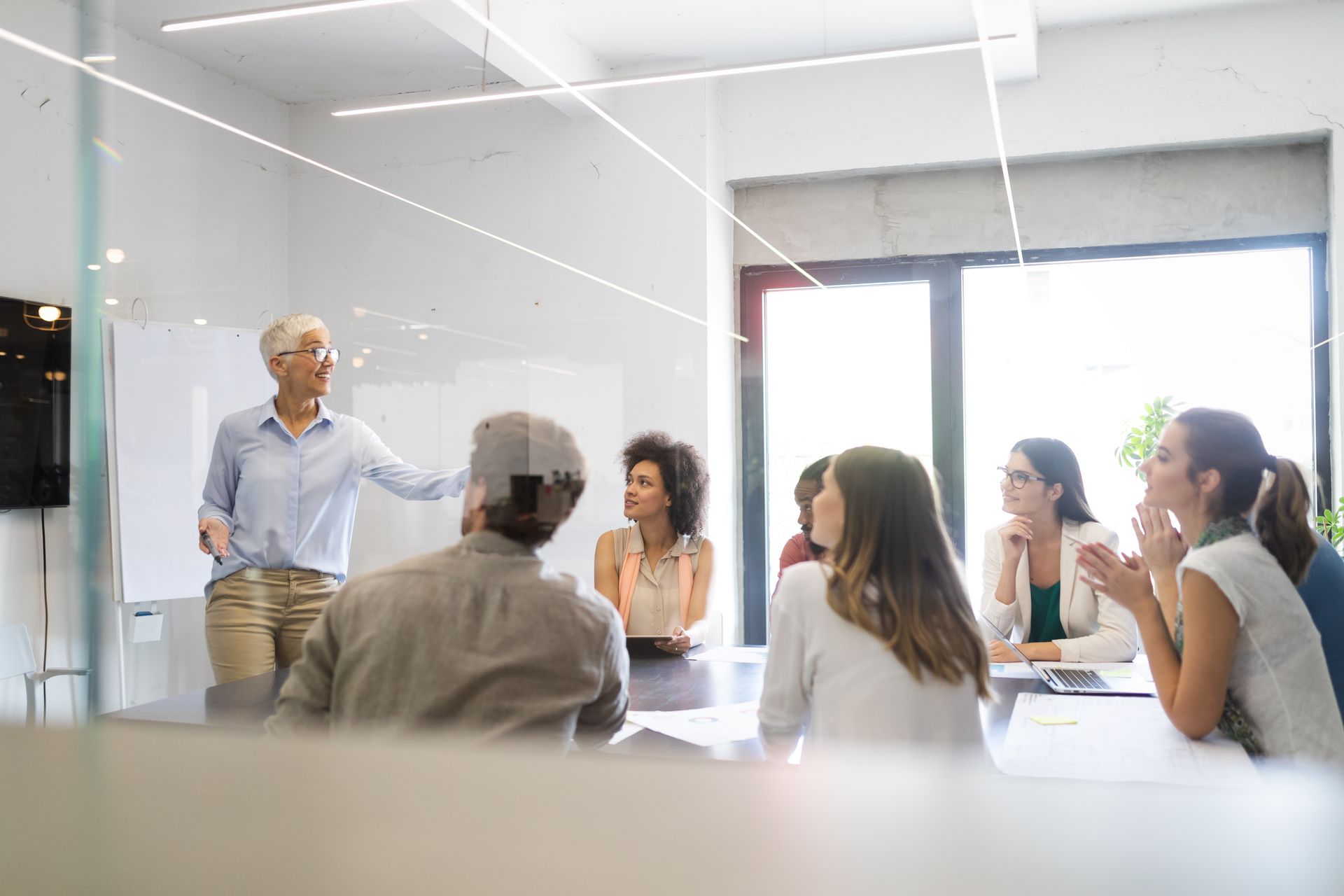 People in a brightly lit room with neon lights, silhouettes against a pink/blue cityscape.