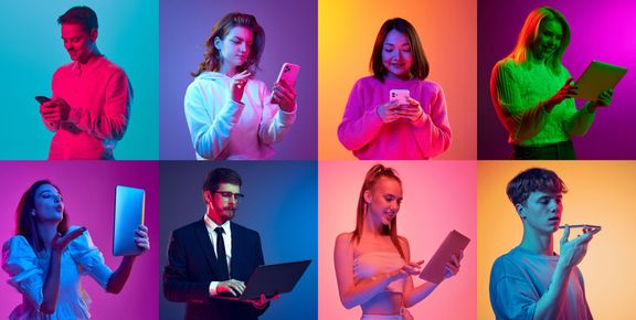 Eight diverse people interacting with devices under colorful studio lighting.