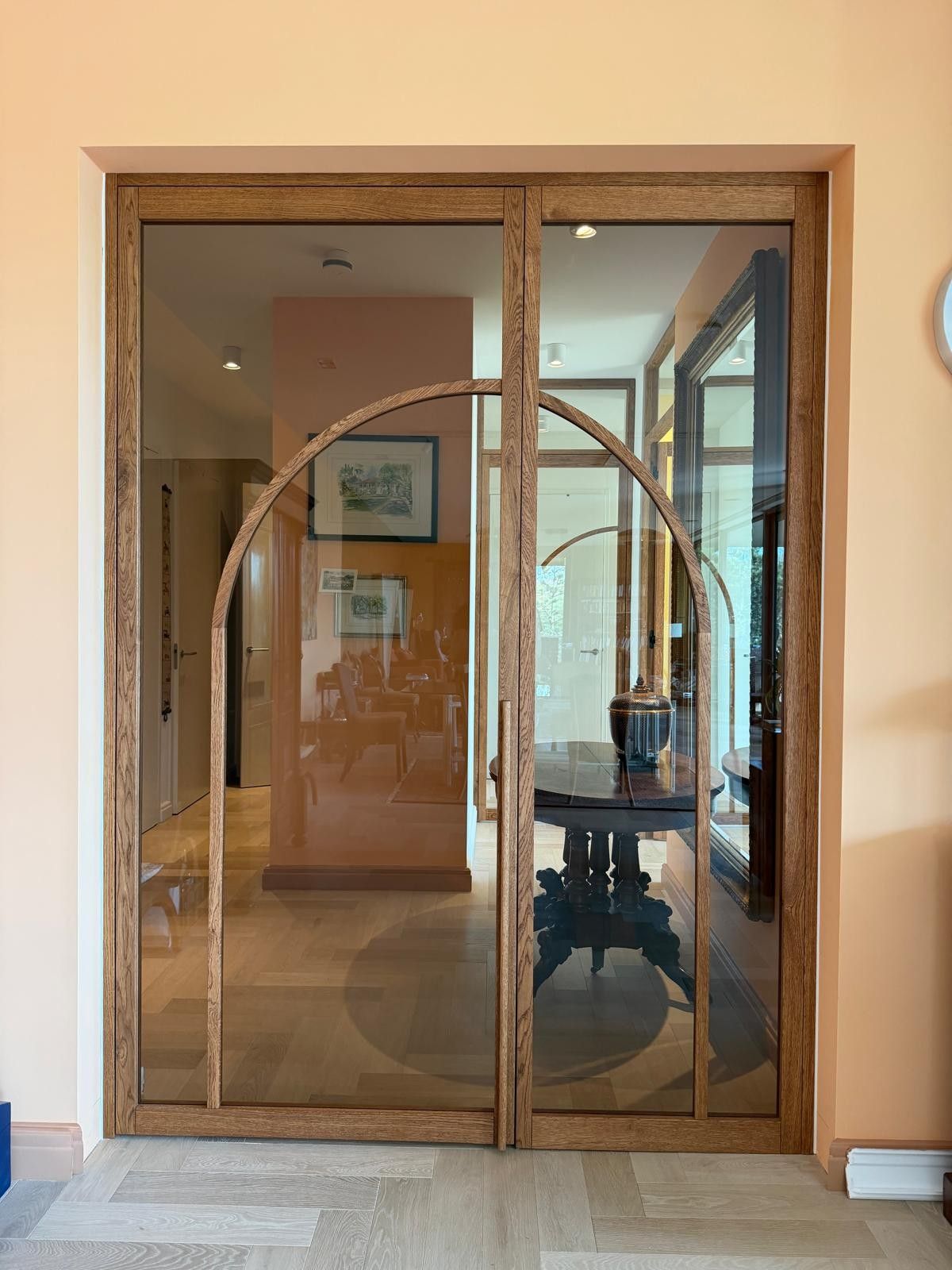 Eiken scharnierdeur met vast paneel of zijlicht. Uitgevoerd met brons getint glas en een mooie organische boog.