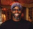 A man with a beard and hat is smiling for the camera.