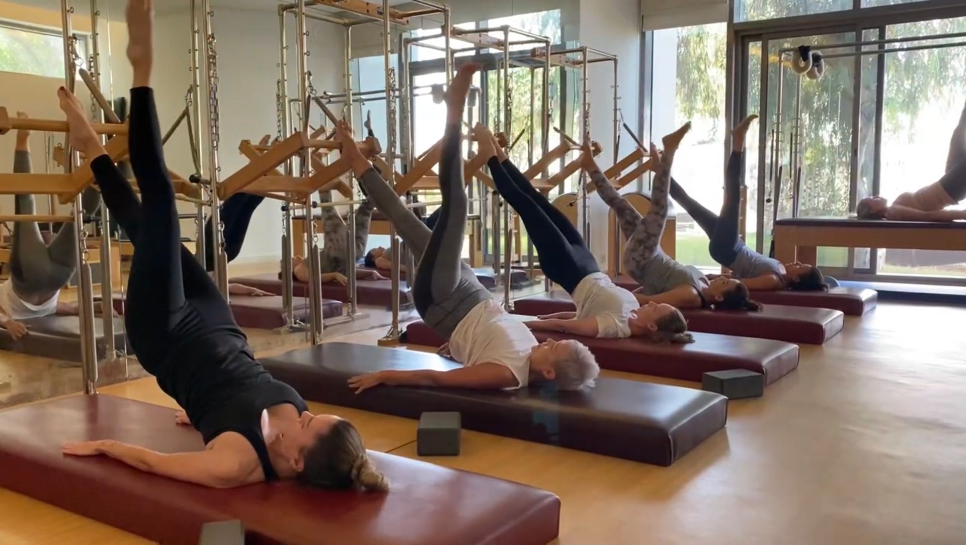A group of people are doing pilates exercises in a gym.