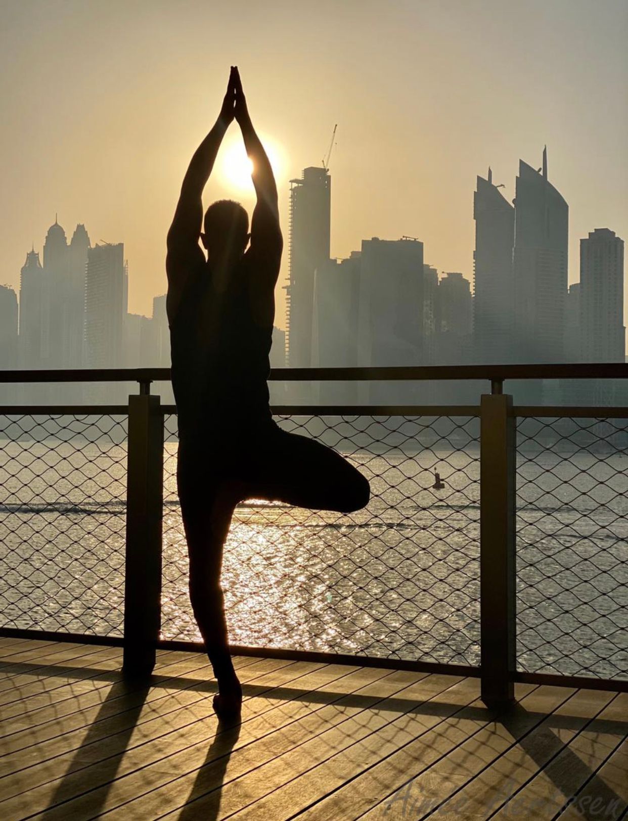 A silhouette of a person standing on one leg in front of a city skyline