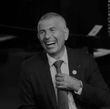A man in a suit and tie is laughing in a black and white photo.