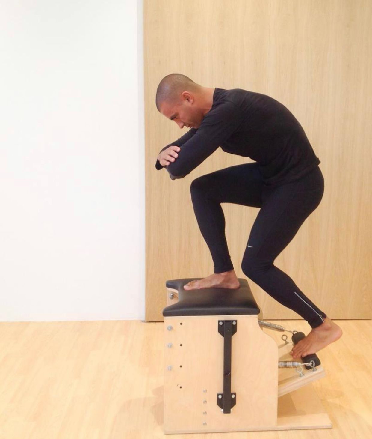 A man is squatting down on a wooden box