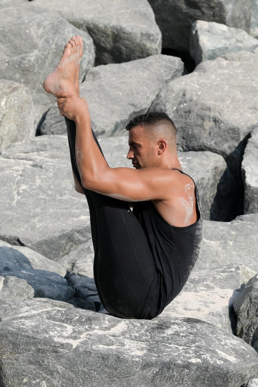 A man is sitting on a rock with his legs crossed.