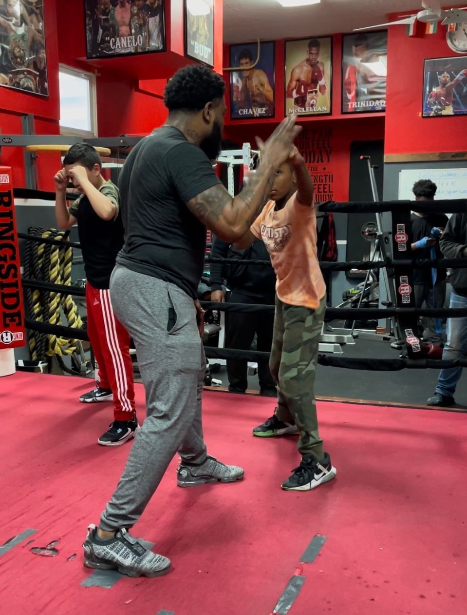A man is teaching a child how to box in a boxing ring.