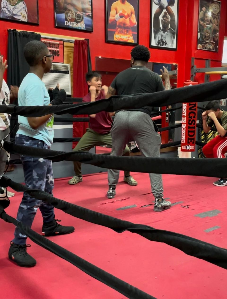 A man in a black shirt is standing in a boxing ring