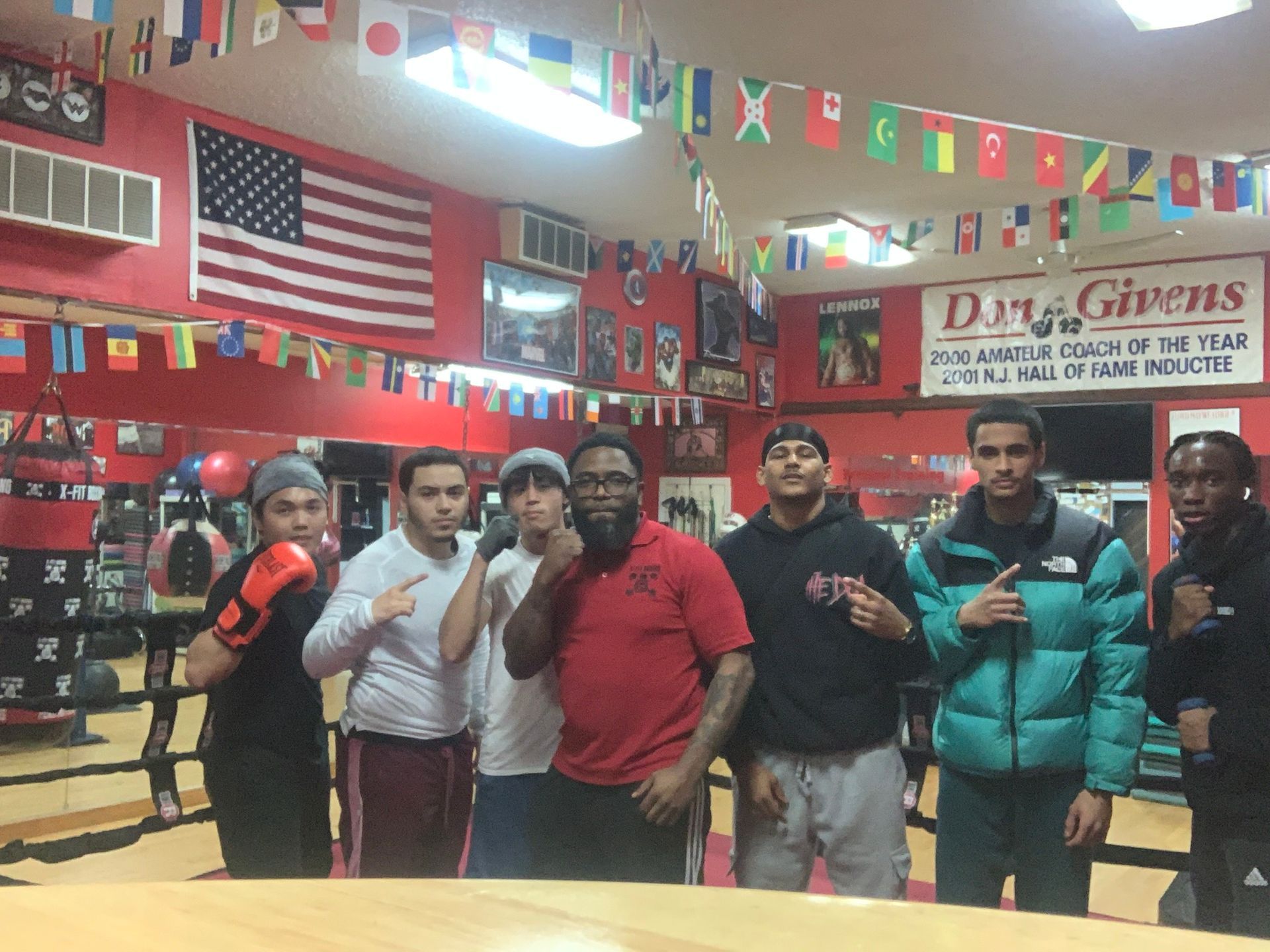 A group of men are posing for a picture in a gym with a sign that says dan givens