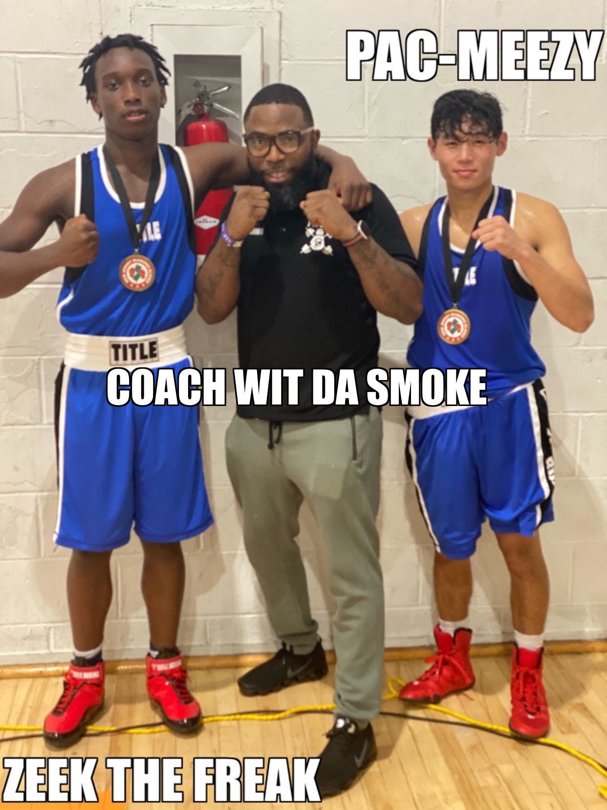 A man is standing next to two boxers with medals on their chests.