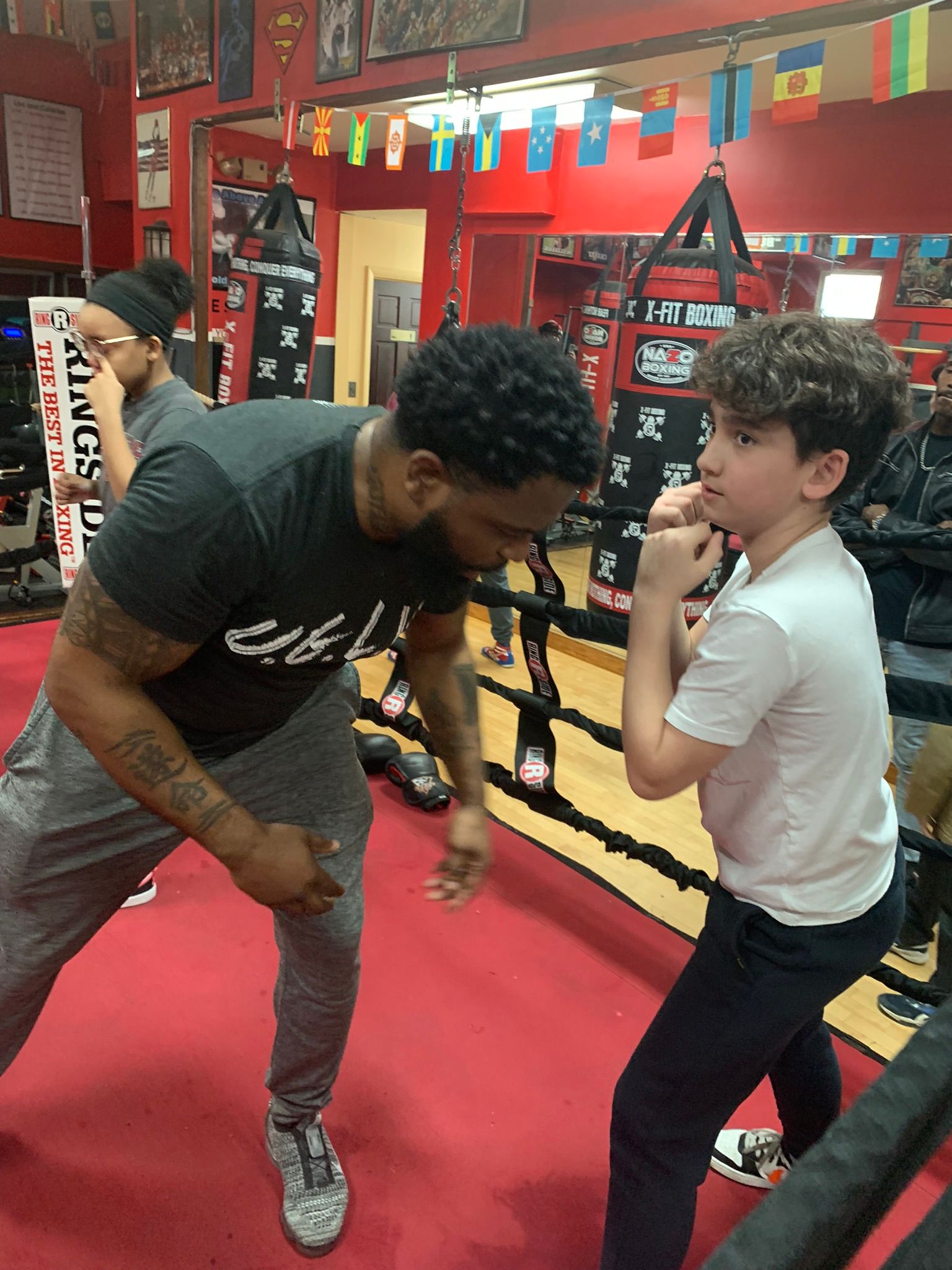 A man and a boy are standing next to each other in a boxing ring.