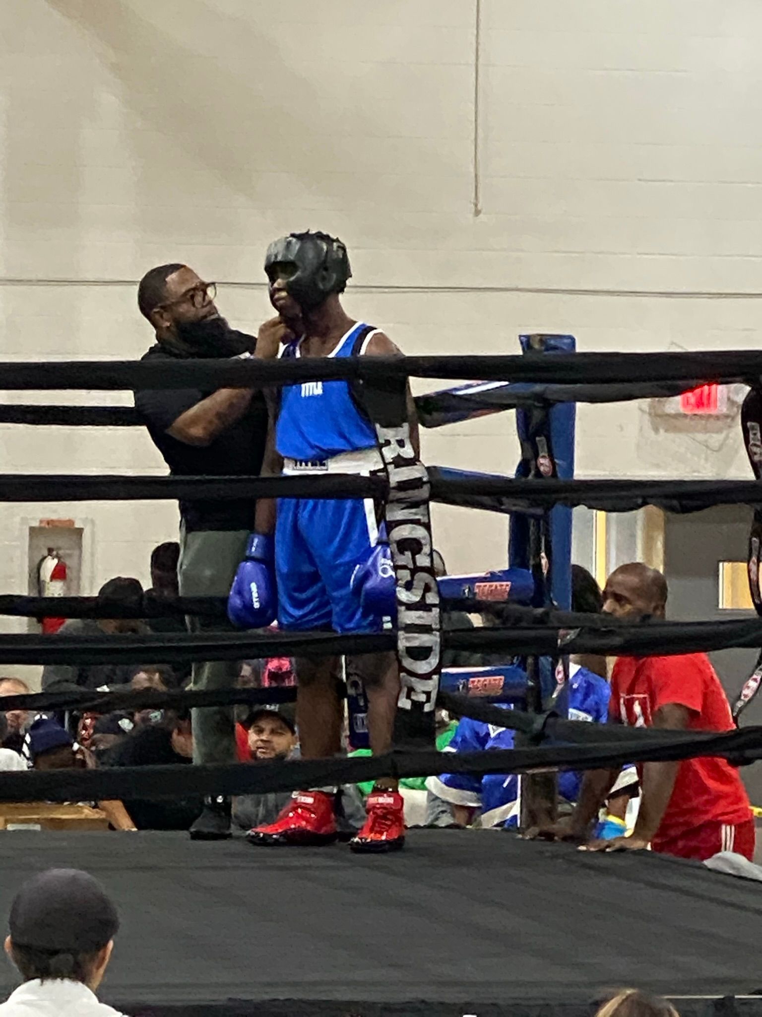A man is standing in a boxing ring talking to another man.