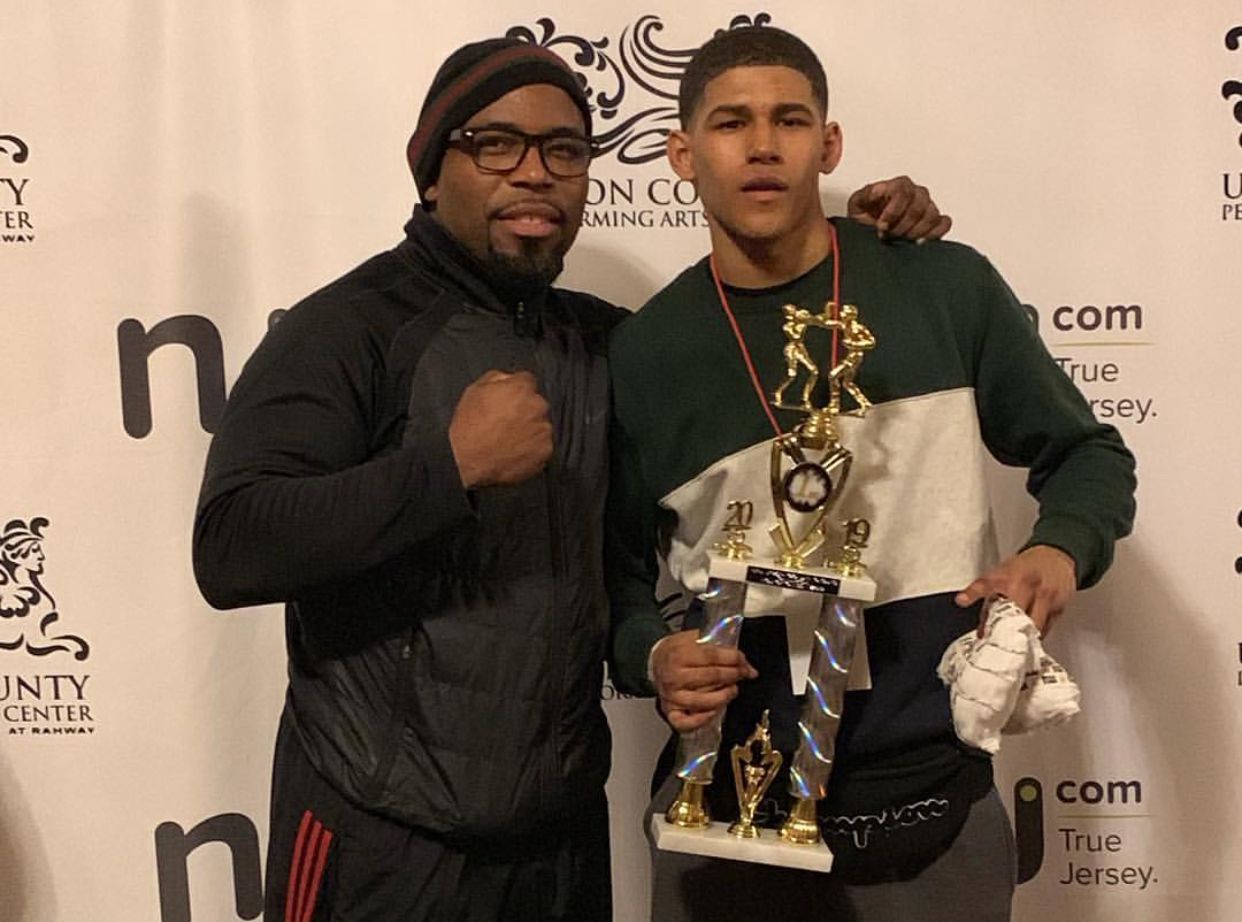Two men standing next to each other holding a trophy