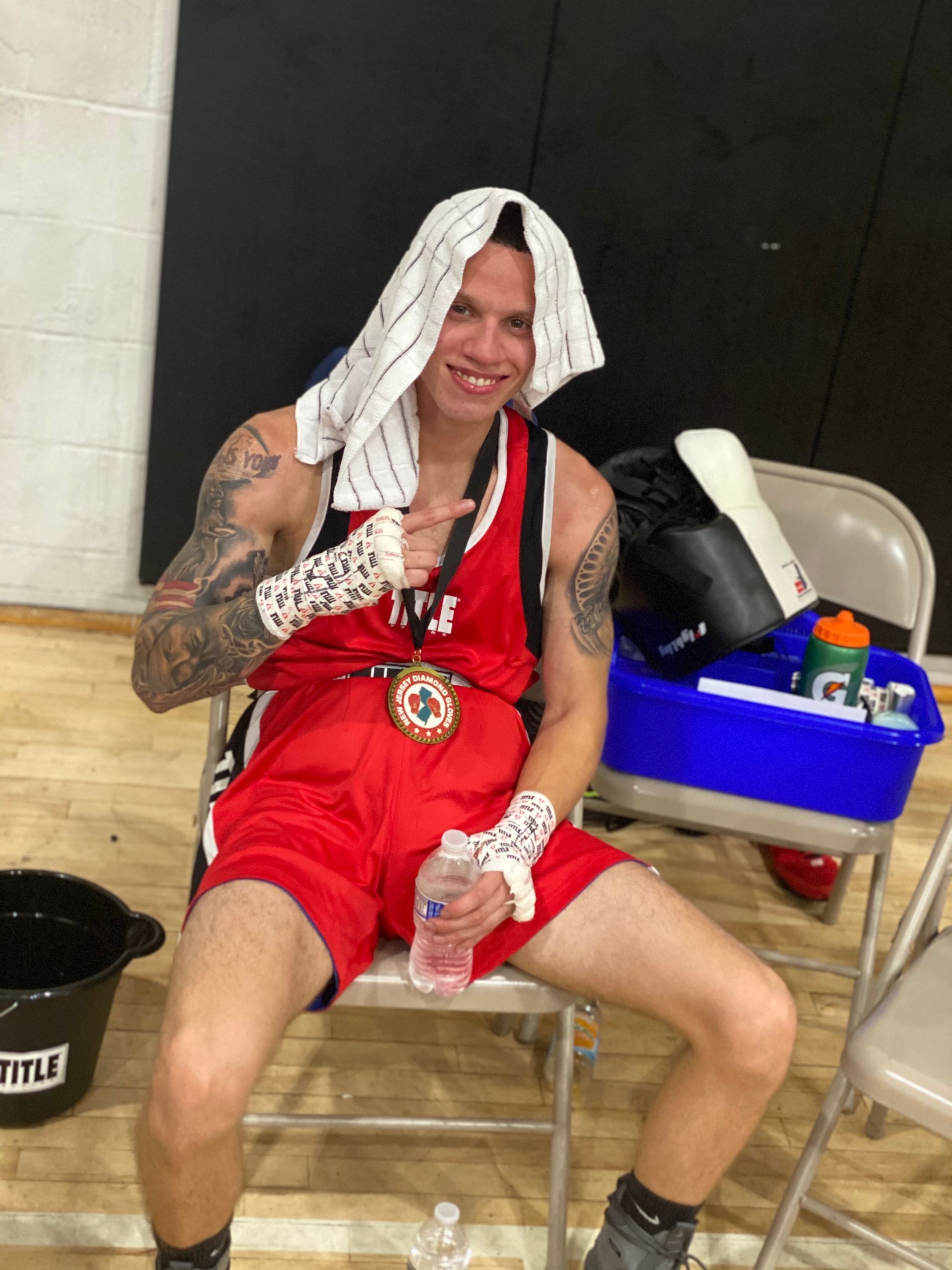 A boxer with a medal on his chest is sitting on a chair