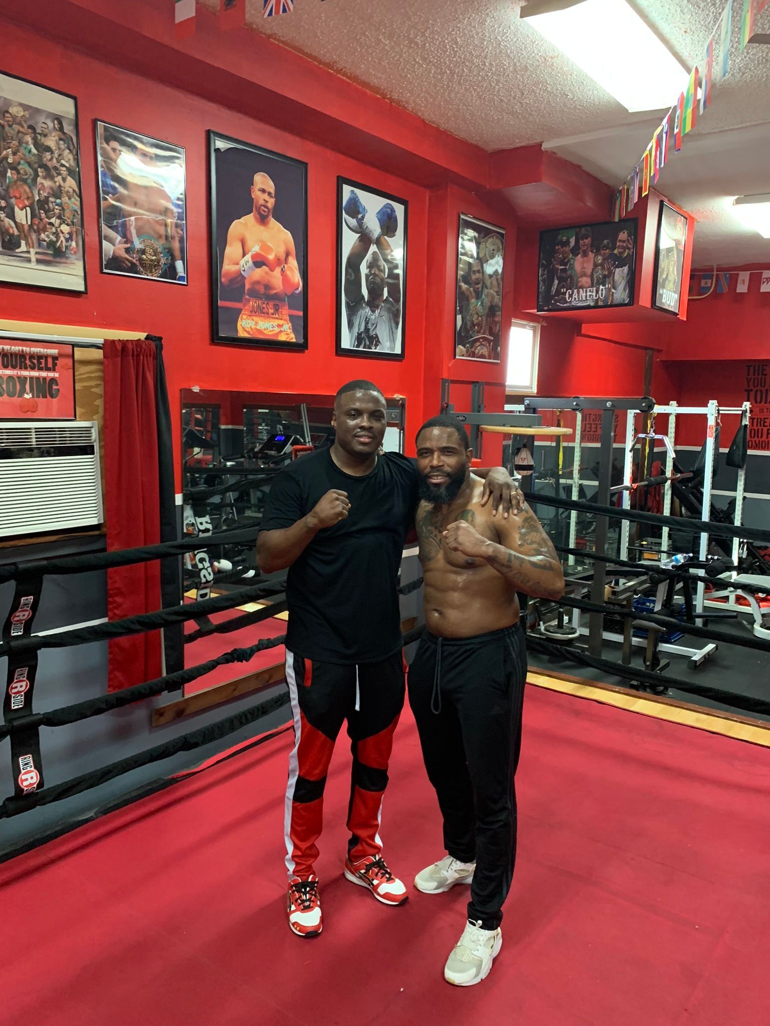 Two men are posing for a picture in a boxing ring.