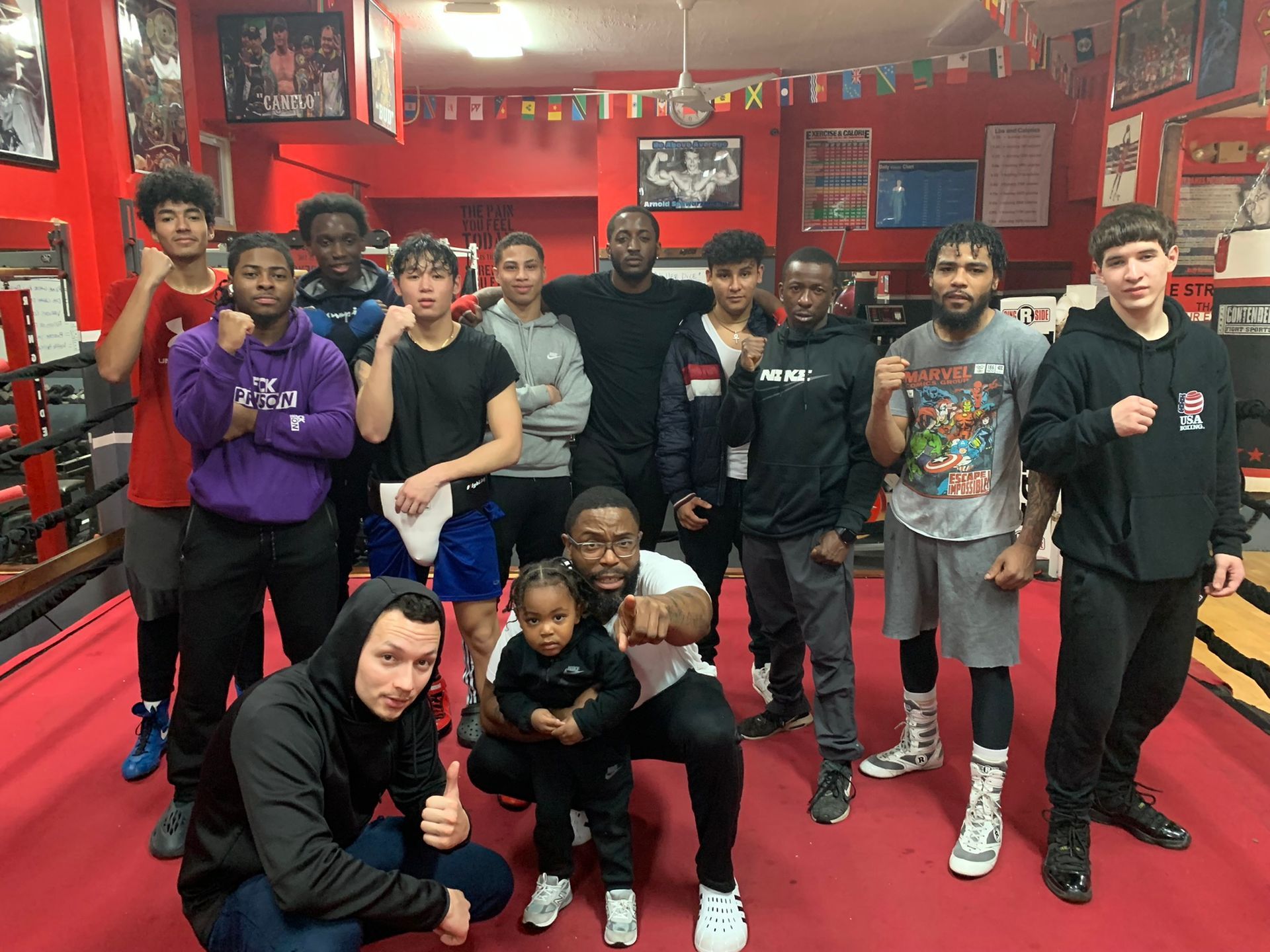 A group of young men are posing for a picture in a boxing gym.
