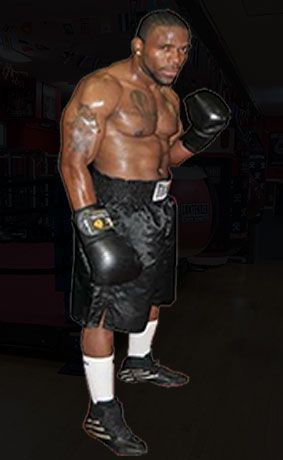 A man is standing in a boxing ring wearing boxing gloves.