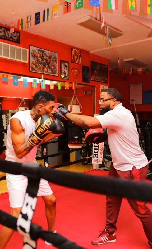 A man is teaching another man how to box in a boxing ring
