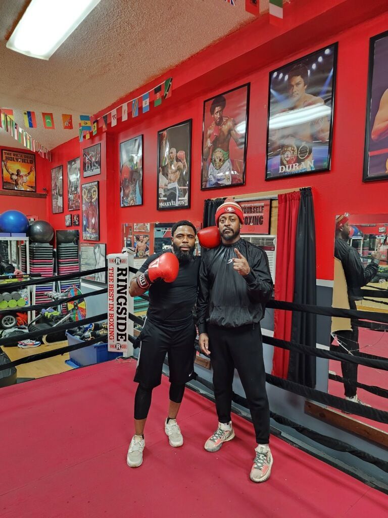 Two men are standing next to each other in a boxing ring.