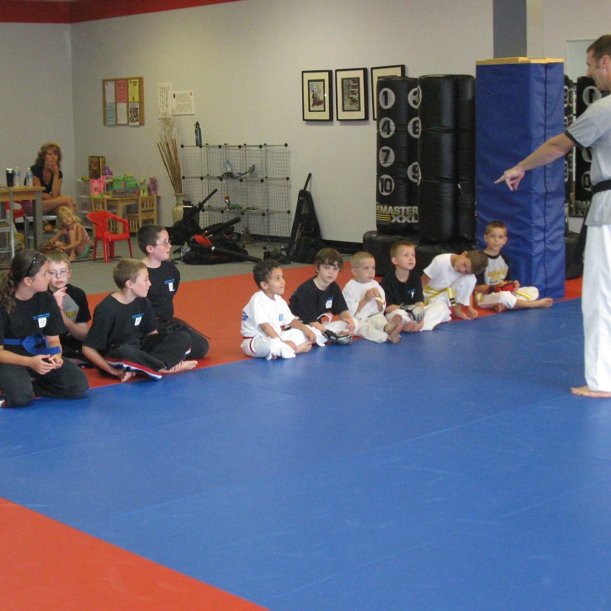 A group of kids are sitting on the floor in a gym