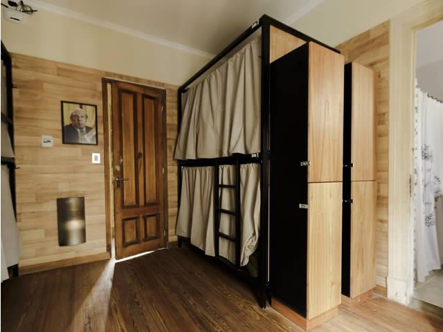 Literas con cortinas en una habitación pequeña con paneles de madera, armarios y una puerta.