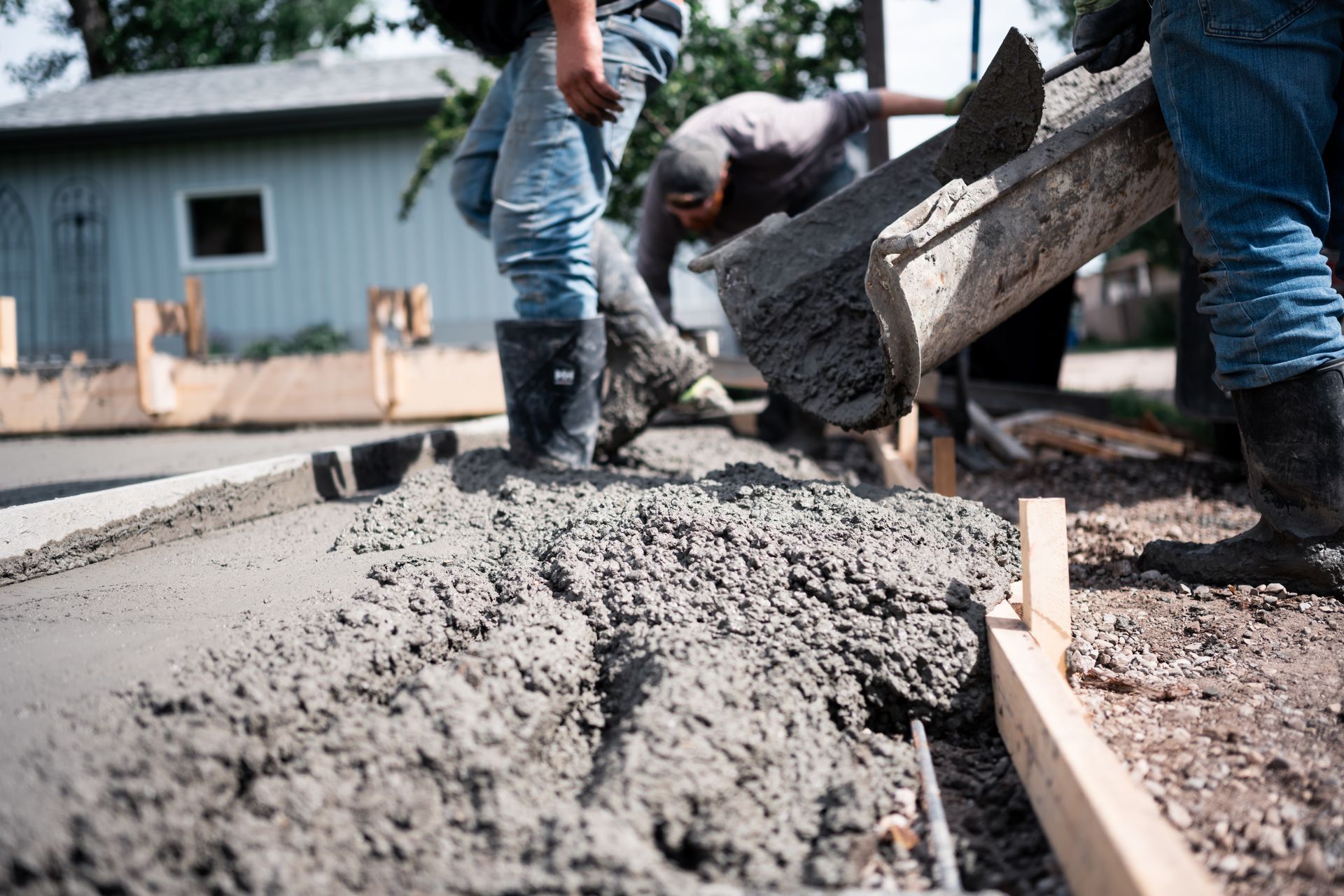 A group of construction workers are pouring concrete on a sidewalk.