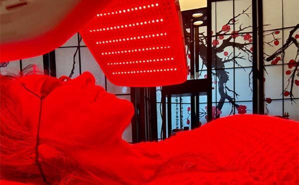 A woman is laying on a bed under a red light.