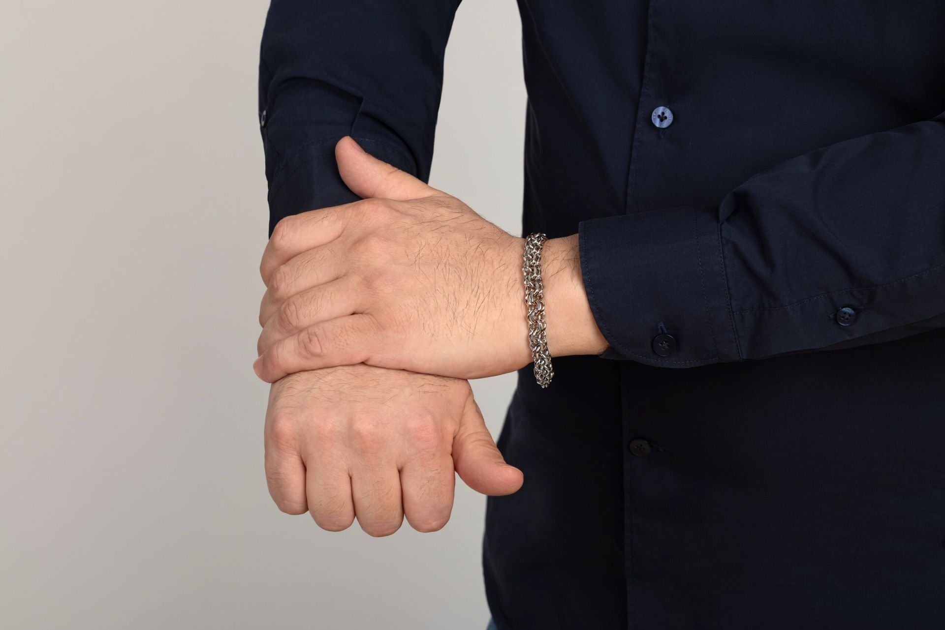 A man wearing a blue shirt and a silver bracelet on his wrist.