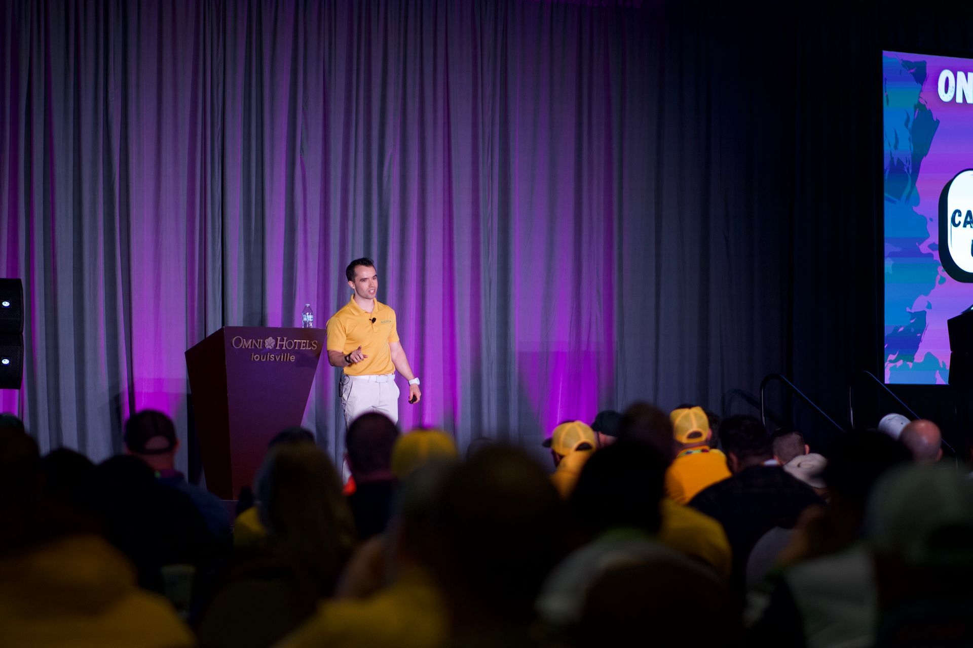 A man is standing at a podium giving a presentation to a crowd of people.
