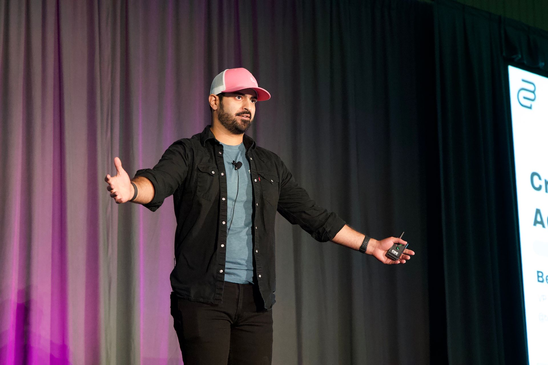 A man in a pink hat is standing on a stage giving a speech.