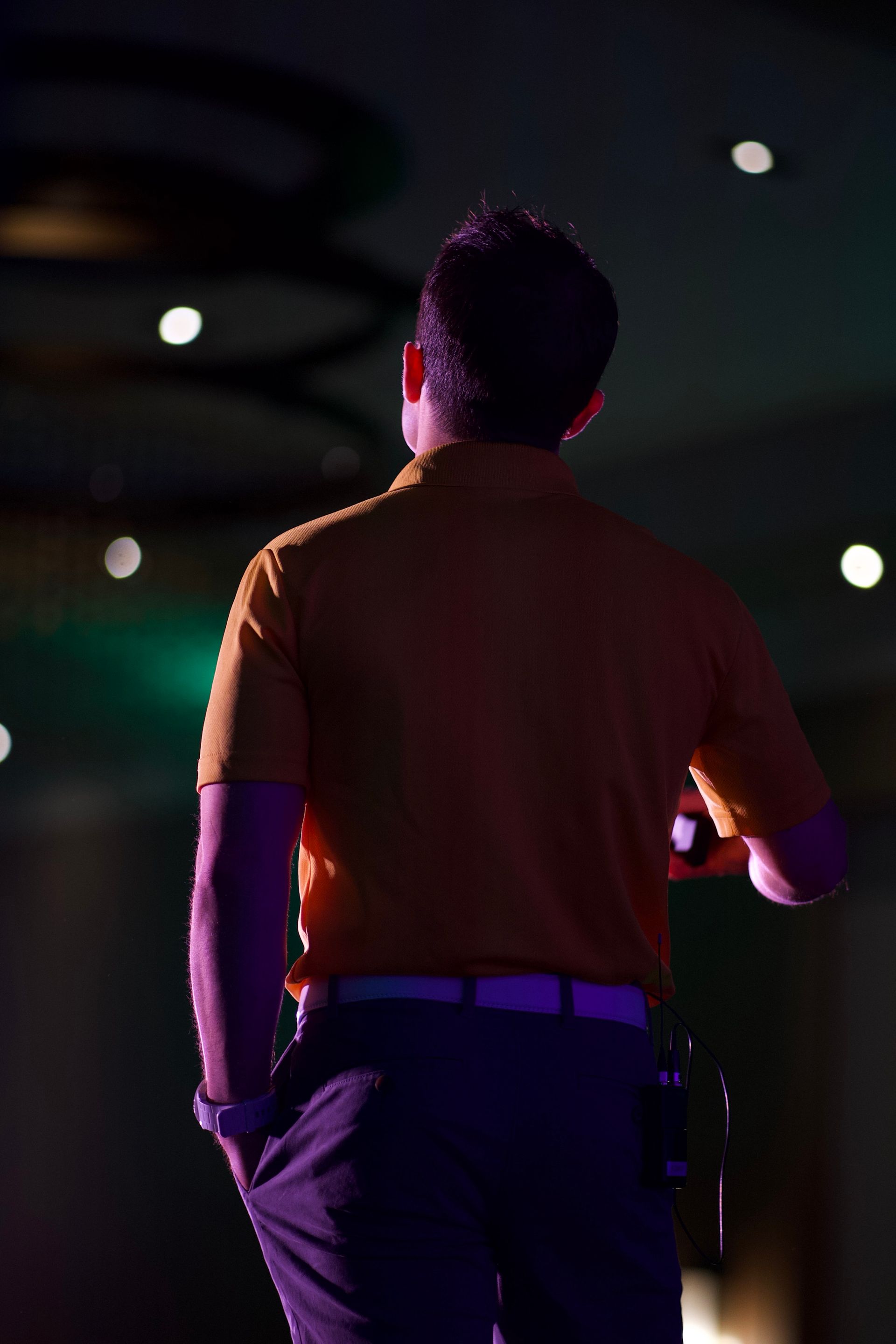 A man is standing in front of a microphone in a dark room.