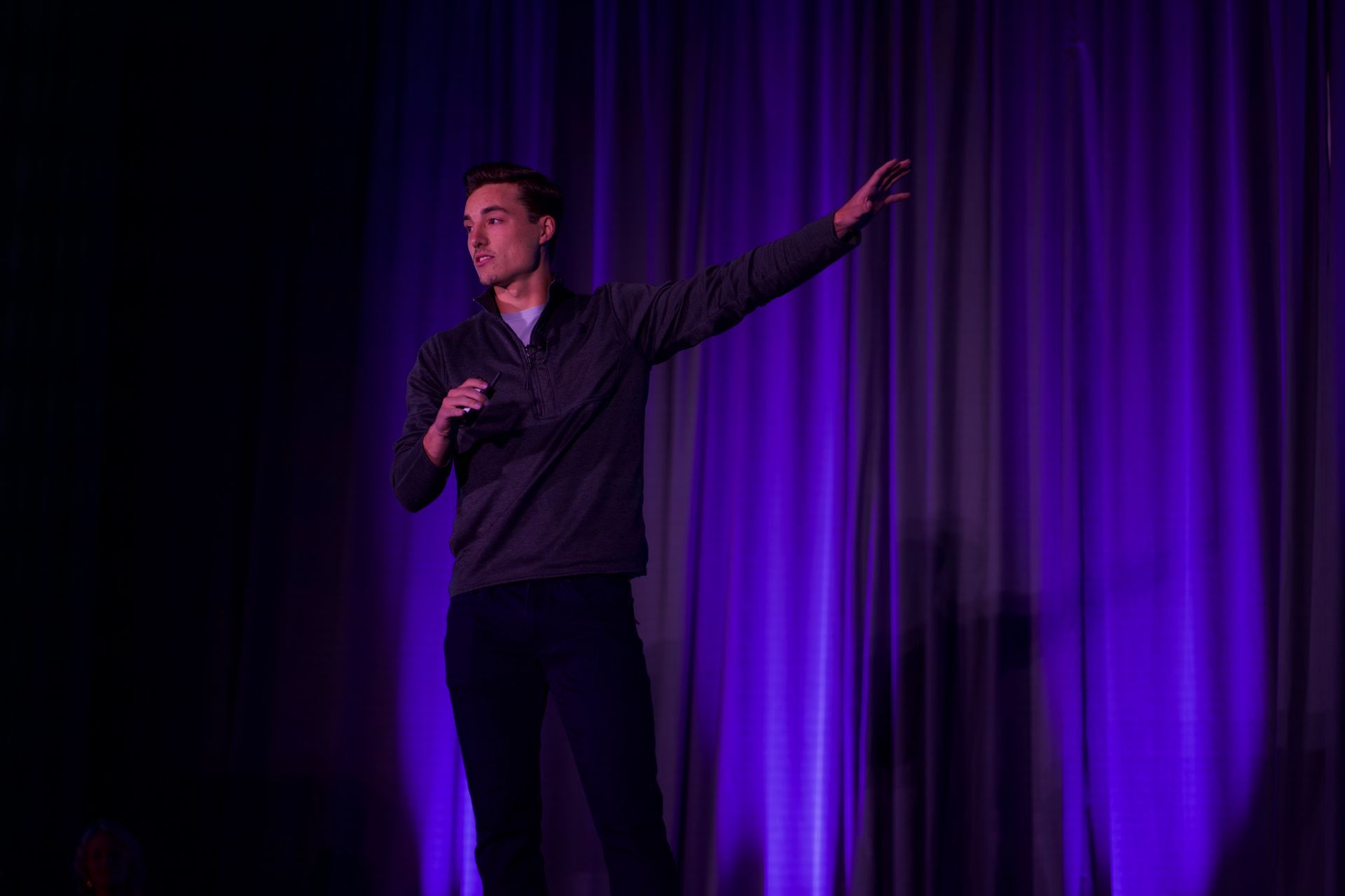 A man is standing on a stage holding a microphone.