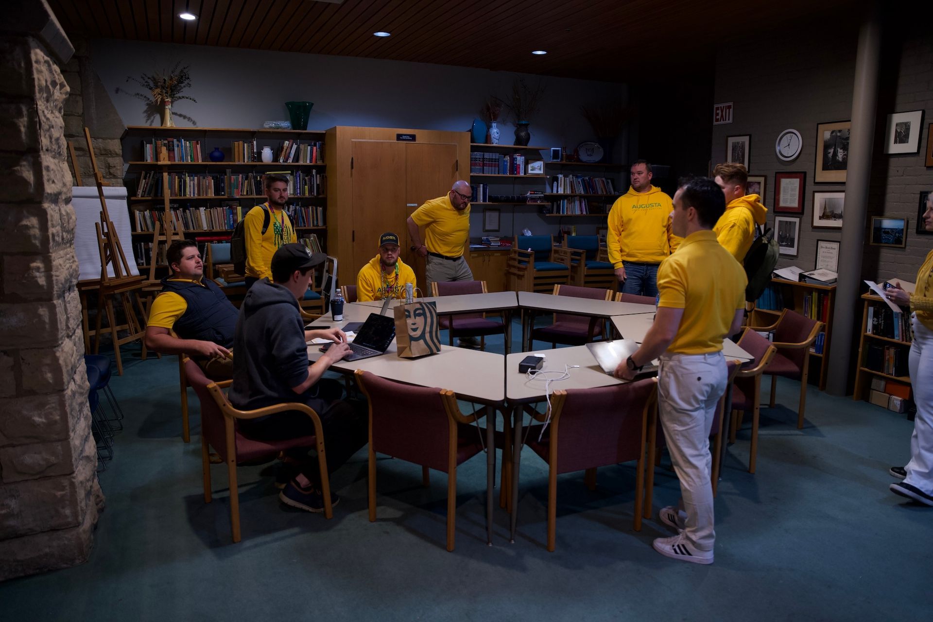 A group of people in yellow shirts are sitting around a table