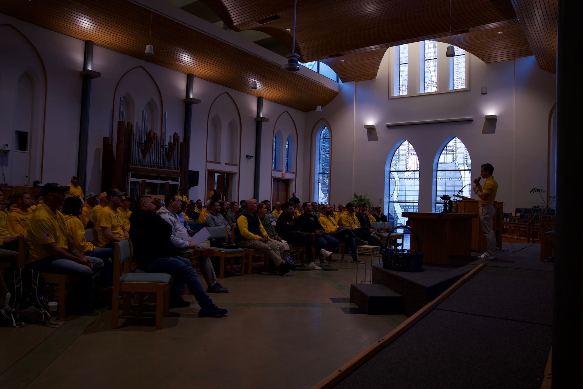 A group of people in yellow shirts are sitting in a dark room