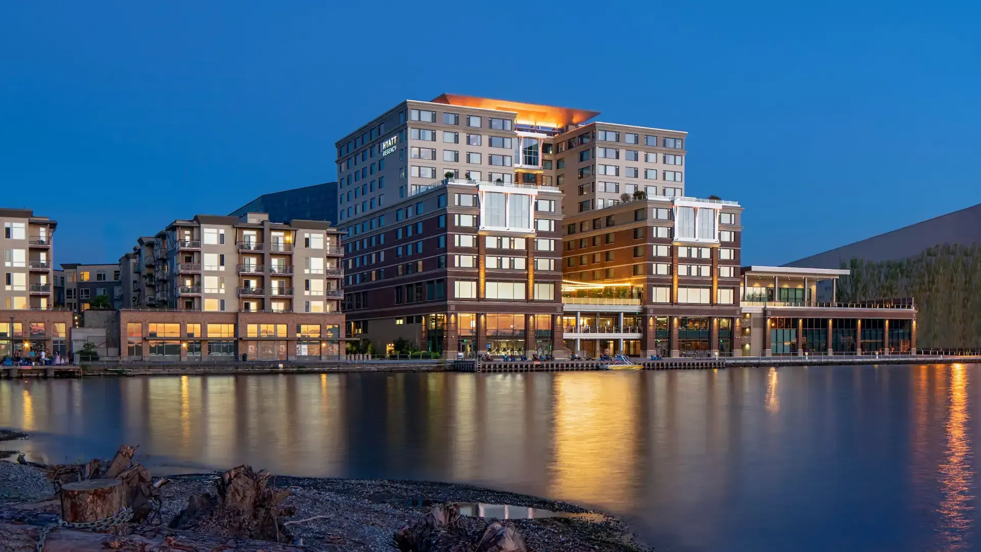 A large Hyatt is sitting next to a body of water at night.