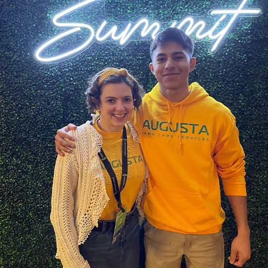 A man and a woman are posing for a picture in front of a sign that says summit