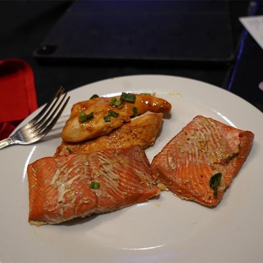 A white plate topped with chicken and salmon with a fork