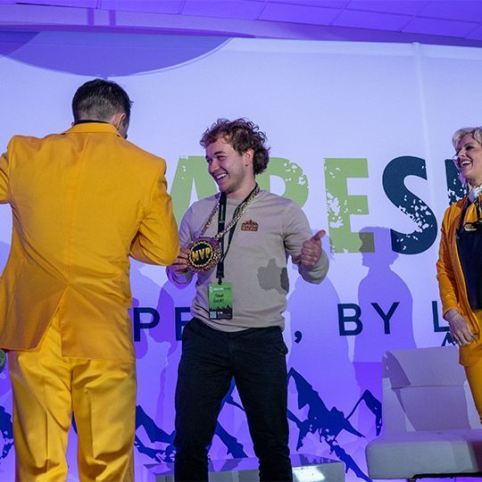 A man in a yellow suit is giving a thumbs up