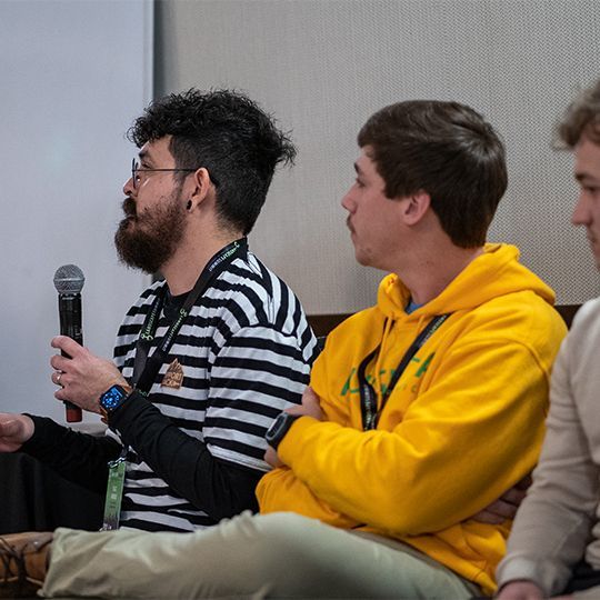 A man in a yellow hoodie is holding a microphone