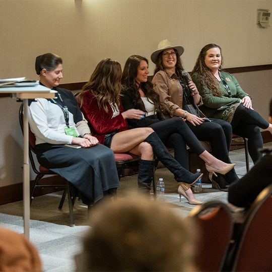 A group of women are sitting in chairs with their legs crossed