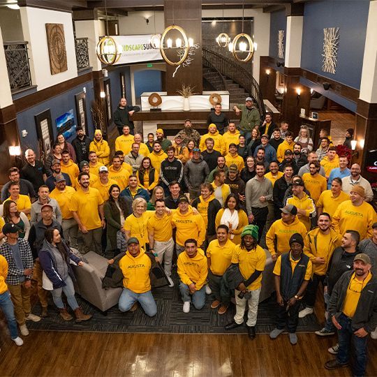 A large group of people in yellow shirts are posing for a picture