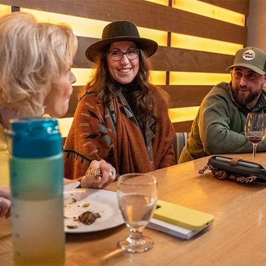 A group of people are sitting at a table with plates of food and glasses of wine.