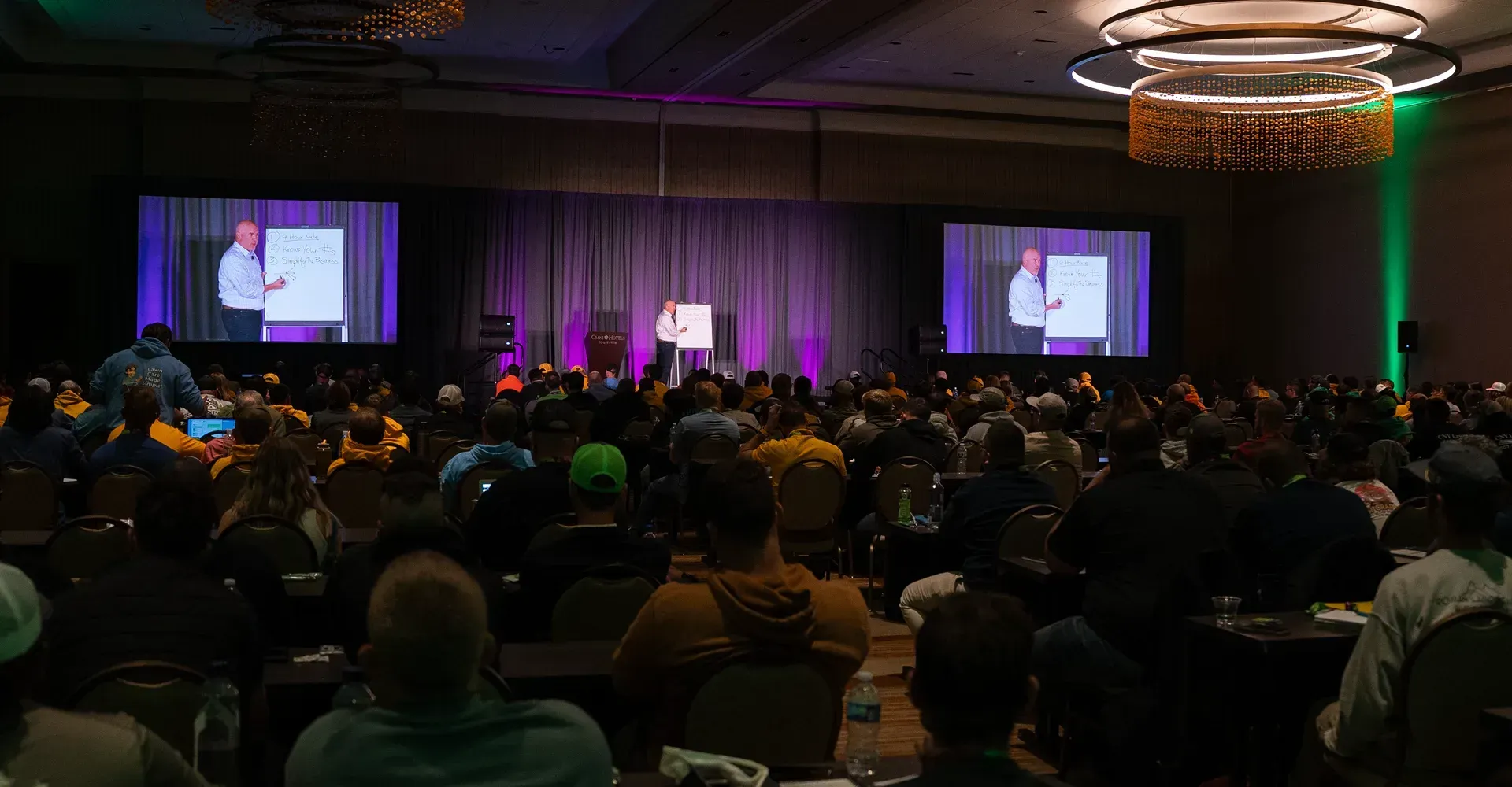 A large group of people are sitting in a conference room watching a presentation.
