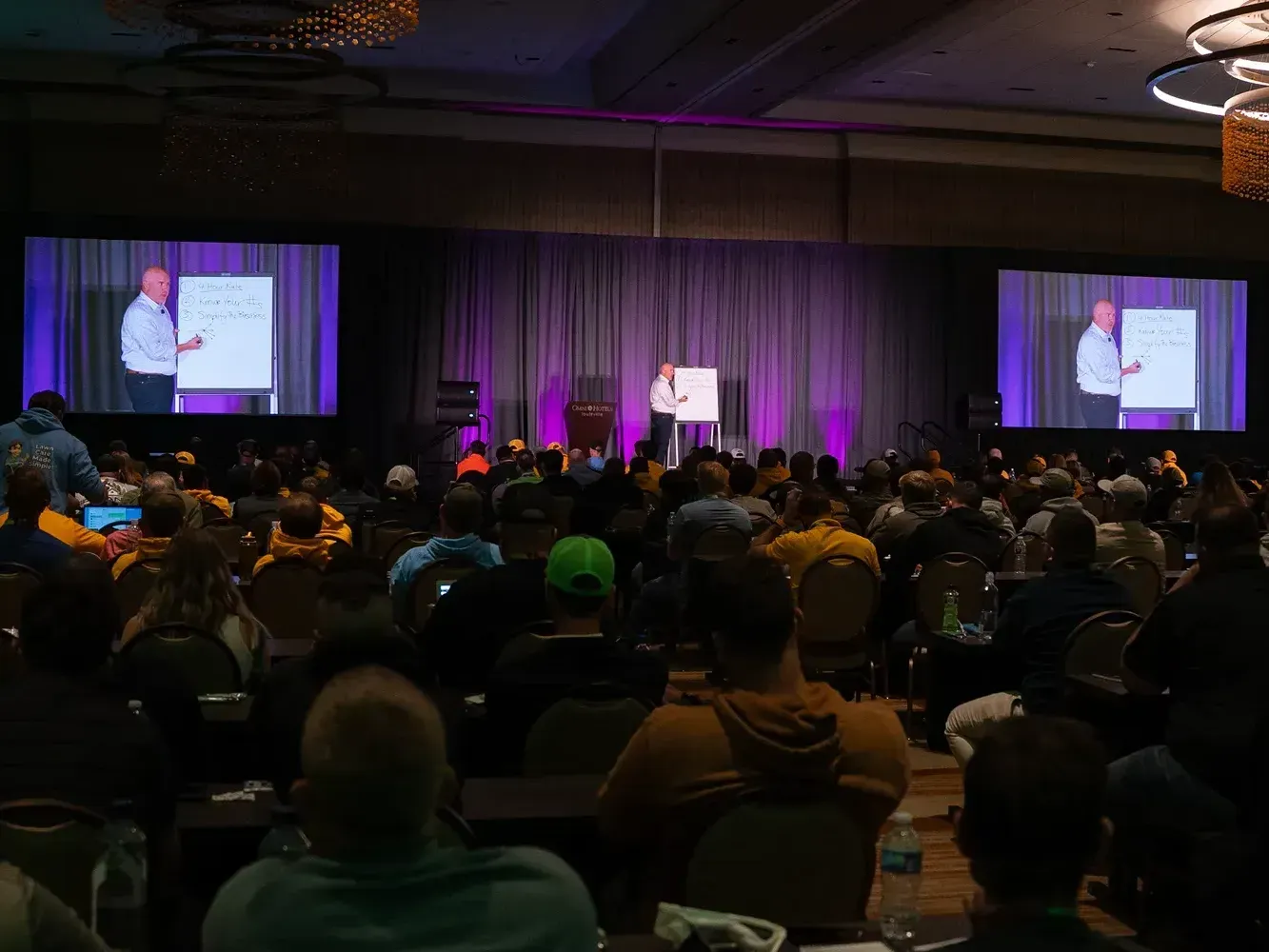 A large group of people are sitting in a conference room watching a presentation.