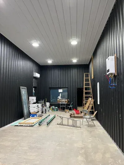 Interior view of a construction site with black walls, white ceiling, and construction equipment.