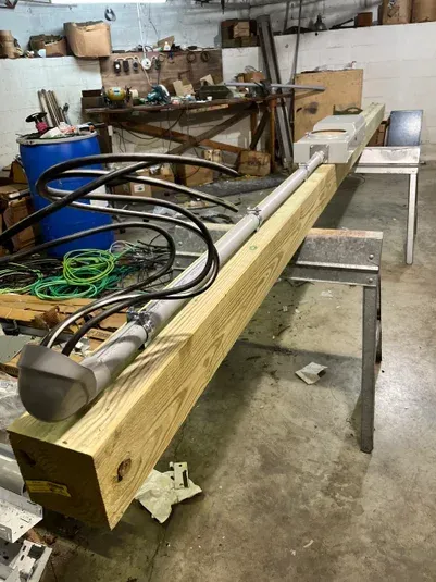 A wooden beam with a light fixture and cables, indoors on a work table.