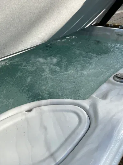 Close-up of a hot tub filled with bubbling, turquoise water; a white edge is visible.